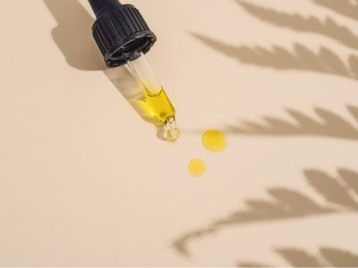 A dropper with jojoba oil drops on a cream background